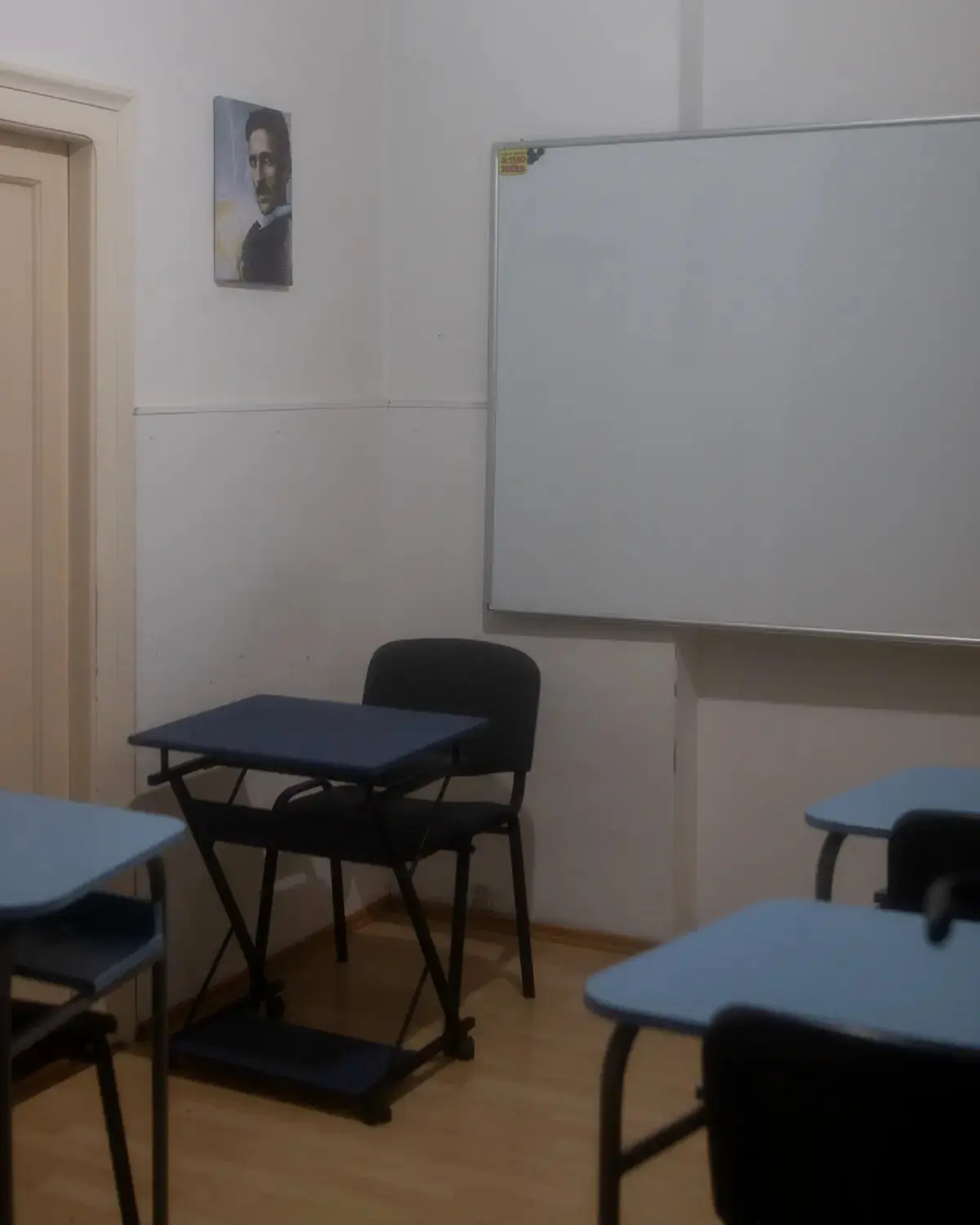 Klupe i tabla u učionici sa Teslinim portretom.